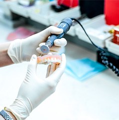 Lab technician altering a full denture in the lab