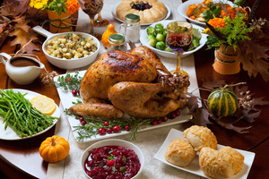 Turkey in middle of table surrounded by other Thanksgiving foods