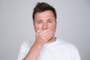 embarrassed man covering his mouth with his hand